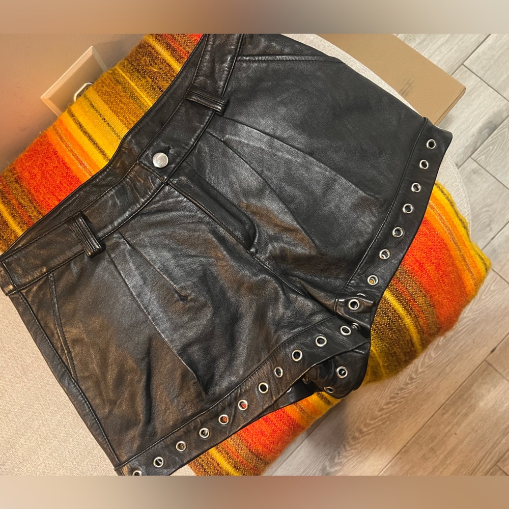 Genuine leather black mini shorts lined with silver metal grommets. Size 8